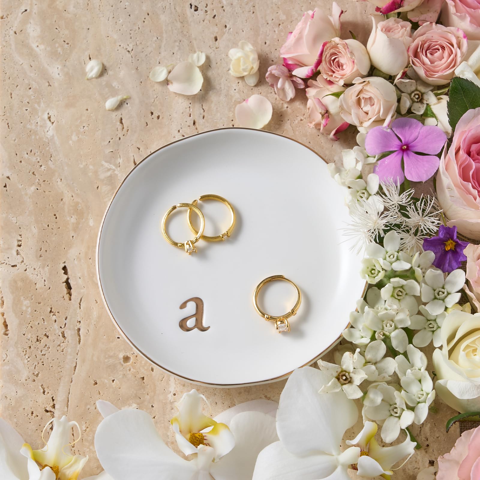 A Lolalet white ceramic jewelry dish featuring a gold "n" initial, elegantly holding an engagement ring, serving as a monogrammed ring holder.