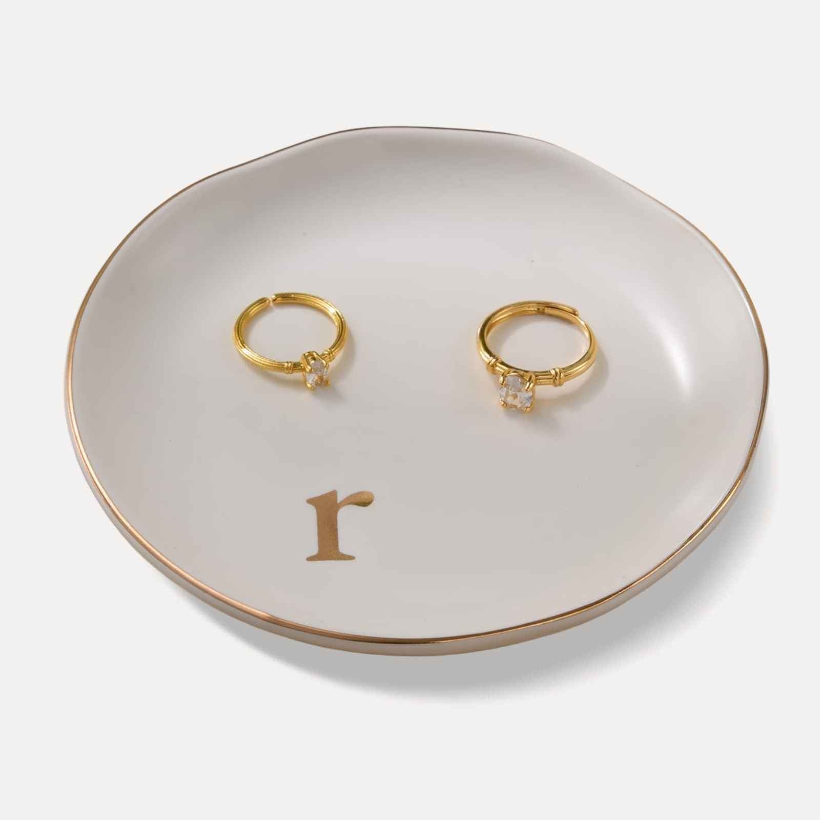 A Lolalet white ceramic jewelry dish featuring a gold "n" initial, elegantly holding an engagement ring, serving as a monogrammed ring holder.