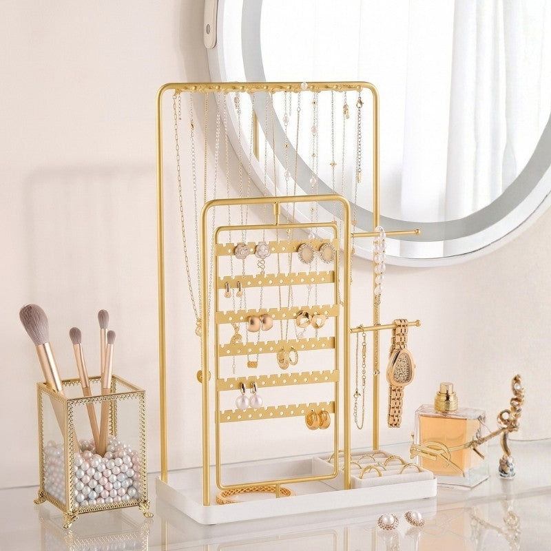 Rotating gold-tone jewelry stand displaying earrings, necklaces, and rings