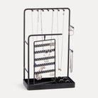 A Black rotating jewelry organizer tower displaying a full collection of earrings, necklaces, bracelets, and rings.