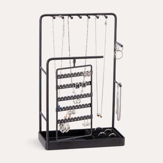 A Black rotating jewelry organizer tower displaying a full collection of earrings, necklaces, bracelets, and rings.
