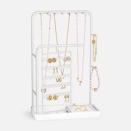 A White rotating jewelry organizer tower displaying a full collection of earrings, necklaces, bracelets, and rings.